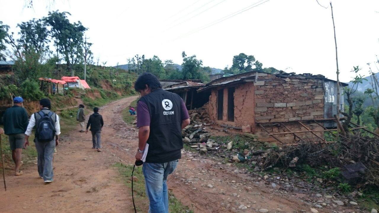 An Oxfam assessment team walks on a dirt path into a village struck by the earthquake.