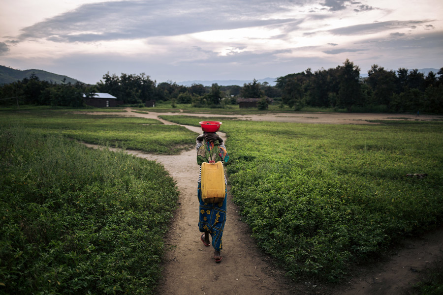 Once Rizini has fetched water, she carries the jerry can filled with 20 liters of contaminated water on her back, held with a strap around her head. Credit: Alexis Huguet/Oxfam