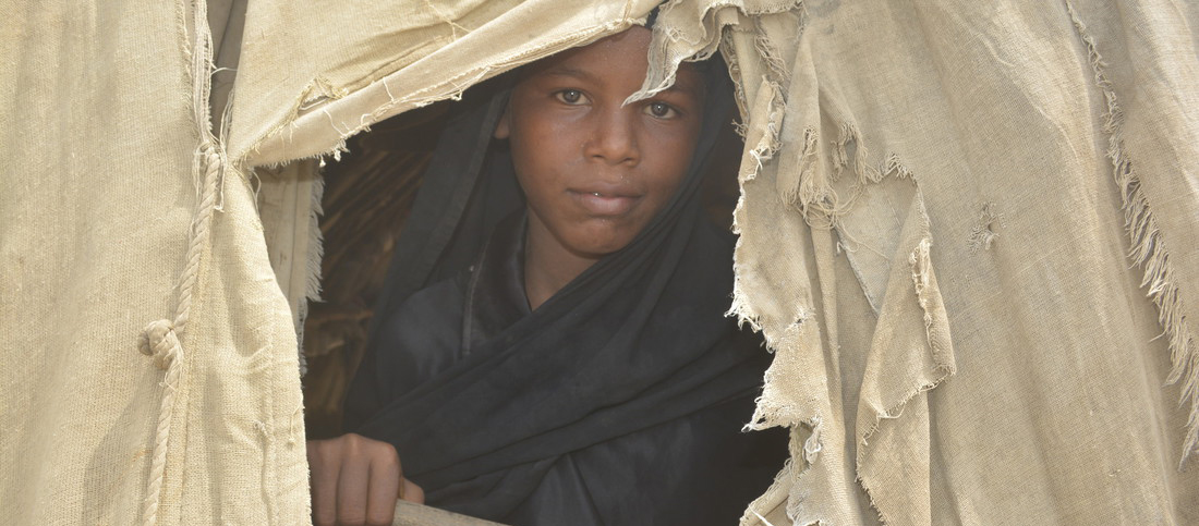 A girl peeps out of her family's tent, Yemen