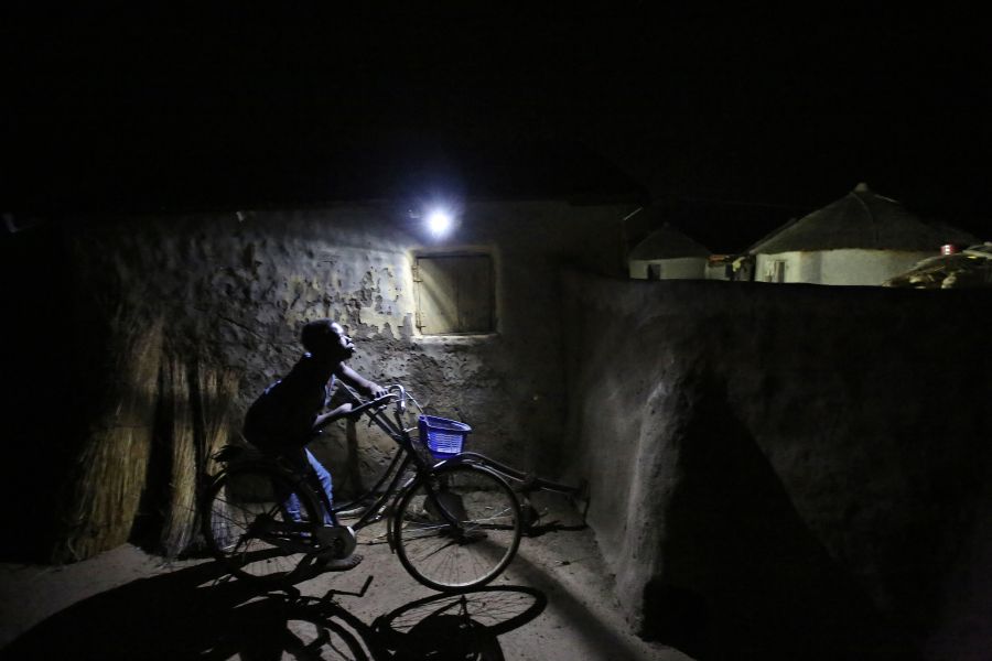 Un garçon passe près d'une lampe à détecteur de mouvement dans le village de Kpatua. Le système d'énergie solaire de cette maison génère et emmagasine de l'électricité qui servira la nuit.