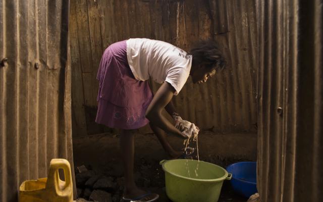 Agnes Adhiambo, 25, domestic worker, washes clothes in Mashimoni village, Mathare, Nairobi, Kenya.