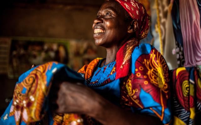 Theresie Nyirantozi (60 yrs) admires tailored fabric she purchased in her home in Kirehe District, Eastern Rwanda.