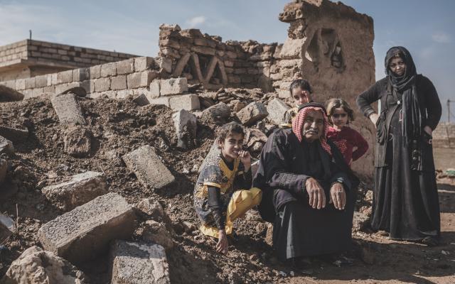 Abu Ahmad sits with his children in the rubble that used to be his home