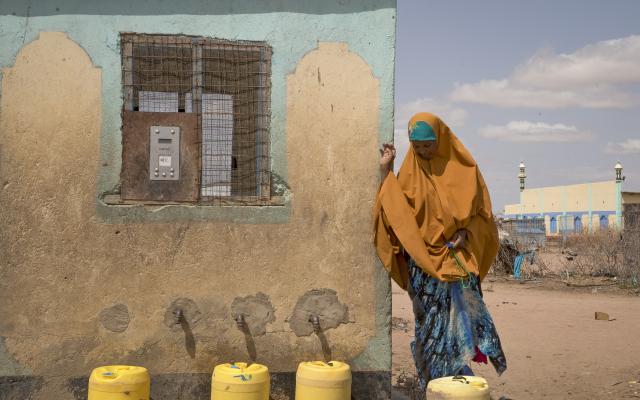 A woman uses her water credit, which is stored in a small, plastic token, to buy water from a Water ATM in Hadado, Kenya.