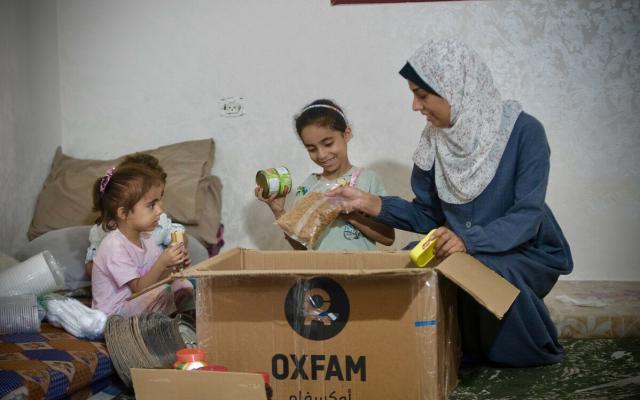 Duaa Mansour and her children are checking the food items in Oxfam food parcel distributed among displaced people due to Israel's war on Gaza.