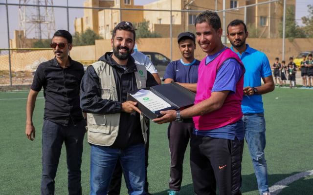Oxfam team delivers an award to the Badia Vultures football coaches.