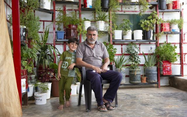 Abu Mohammad* and his son in their front yard, with the plant's pots.