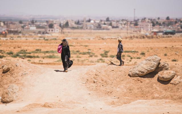 Women and child return from to the Za’atari Refugee Camp through the berm.