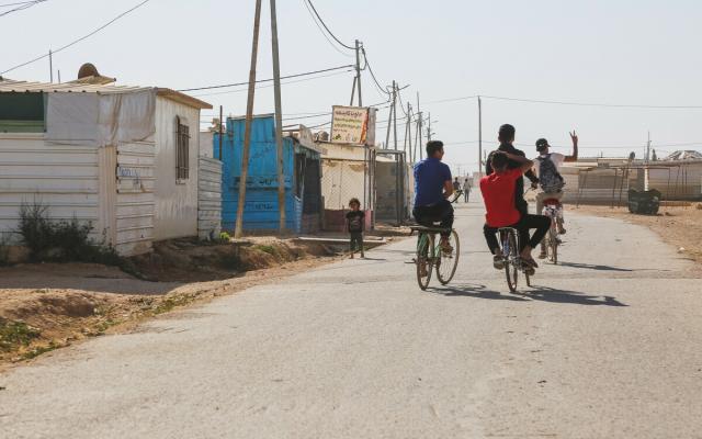 A group of young refugees in Za’atari Refugee camp riding bicycles.
