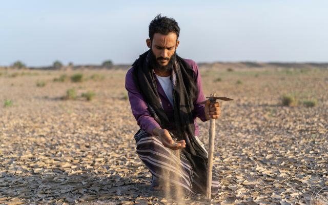 Bakeel Jahes holds the sand in his hand from the desertificated soil underneath him. Jahes’s family lost almost 60% of their land in Al-Wahat city, Lahj governorate, to desertification, floods, and war.