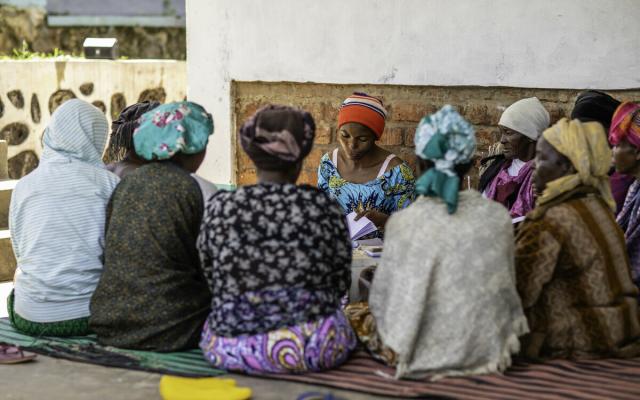 Murega Bahat leads a money collection session for the A.V.E.C savings group in Burhinyi chiefdom, South Kivu, DRC.