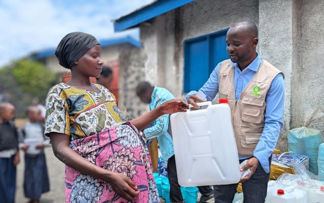Muhawe Myriam Charmante receiving Non-Food Item kits from Oxfam staff.