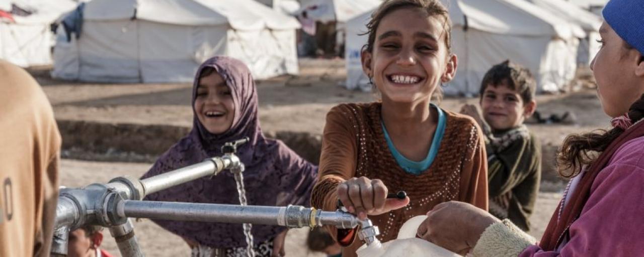 Children fill bottled with clean water at a tap stand in Hassansham camp in east of Mosul, Iraq. (Photo: Tegid Cartwright/Oxfam) https://www.oxfam.org/en/what-we-do/issues/water-and-sanitation