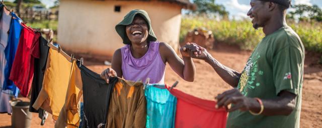 Ulita Mutambo’s husband Muchineripi Sibanda helps her hang up laundry outside their home in Ture Village, Zvishevane region, Zimbabwe.  Credit: d'Unienville/Oxfam