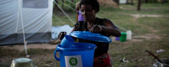 Maria puise de l'eau avec un seau donné par Oxfam dans le camp de Bangula, au sud du Malawi. Crédit : Philip Hatcher-Moore / Oxfam