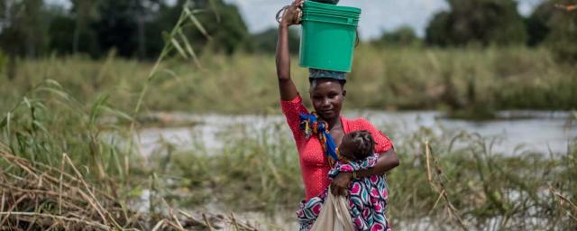 Regina, 20 photographed with four-year-old Mayasa, after wading through floodwater on the road to Metuje in northern Mozambique. Credit: Tommy Trenchard/Oxfam