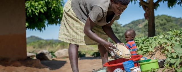 28 years old Edna washes dishes outside her home in Masvingo District, Zimbabwe.