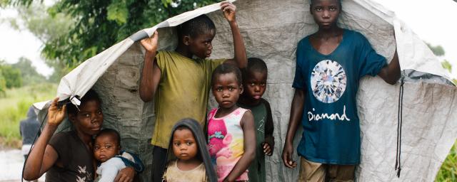Maria, 31, with her six children with their only belongings sheltering from the rain by the side of the road.