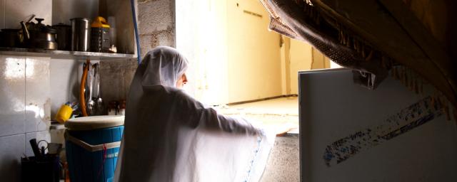 Najwa*, 48, is standing in her partially damaged kitchen in Harasta, Eastern Ghouta, Rural Damascus.