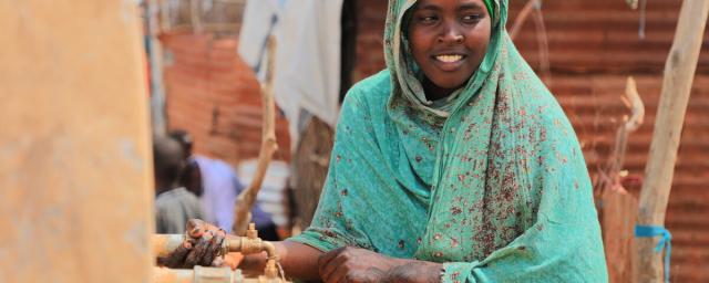 Aqiqah, a mother of three collects water from an Oxfam-constructed water tank in Beledweyne, significantly reducing the burden on women and girls who previously had to walk long distances to access water.