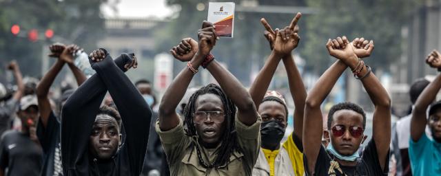 Demonstrators make signs with their arms in front of Kenyan police officers during a demonstration against tax hikes as Members of the Parliament debate the Finance Bill 2024 in downtown Nairobi, on June 18, 2024.
