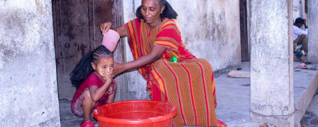 Ms. Birey Yohans Werede washes her daughter’s hair outside their shelter in Hitsats, Asgede Woreda, Tigray. (Photo: Oxfam)