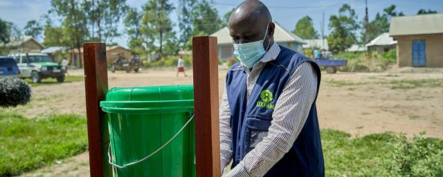 A deacon helping a parishioner wash hands to limit the spread of Ebola in Bunia