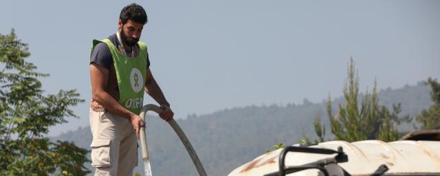 An Oxfam staff member refills a water tanker in Ballouran, rural Latakia.