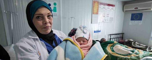 A doctor holds a baby in the maternity center in Za’atari refugee camp, Jordan. A doctor holds a new born baby, Za'atari Refugee Camp, Jordan