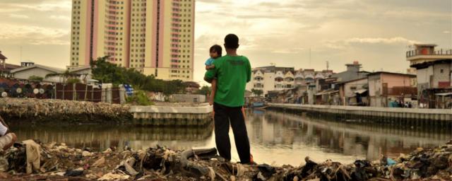 Looking at the future: a father holds his daughter as he stands on a site where residents have recently been evicted from nearby luxury apartments in North Jakarta. Photo: Tiara Audina/Antropology UI 