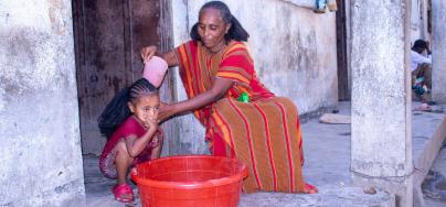 Ms. Birey Yohans Werede washes her daughter’s hair outside their shelter in Hitsats, Asgede Woreda, Tigray. (Photo: Oxfam)