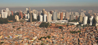 Densely packed low-rise homes in the foreground contrasted with modern high-rise buildings in the background, highlighting urban inequality.