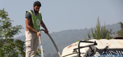 An Oxfam staff member refills a water tanker in Ballouran, rural Latakia.