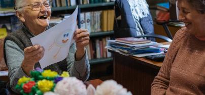 Two women smiling while looking at a piece of paper with a child's drawing.