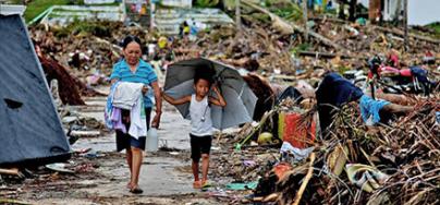 A woman and a child walk among the rubble in a village in Eastern Samar, after the typhoon Haiyan hit the Philippines. Credit: Jire Carreon/Oxfam