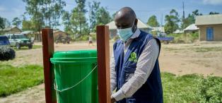 Roger Kalimira (Oxfam WASH officer) using handwashing stand.